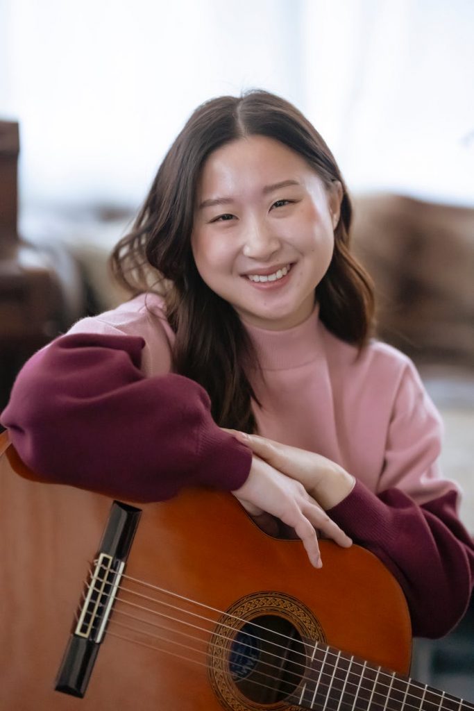 smiling asian woman with guitar in studio